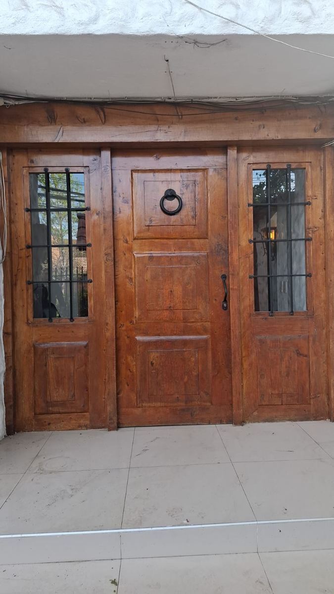 Puerta de entrada de madera maciza, con laterales de vidrio y rejas, recuperada de una demolición de SG Ingeniería y Demoliciones en Santiago